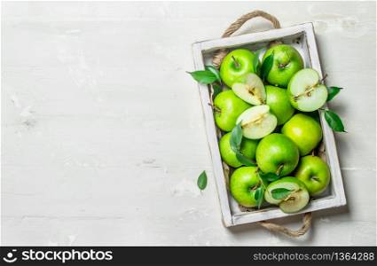 Green apples in a wooden tray. On white rustic background .. Green apples in a wooden tray.