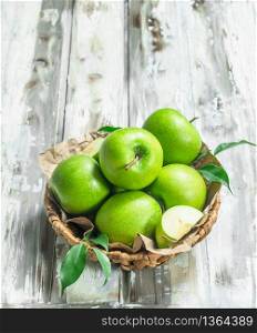 Green apples in the basket. On a white wooden background.. Green apples in the basket.