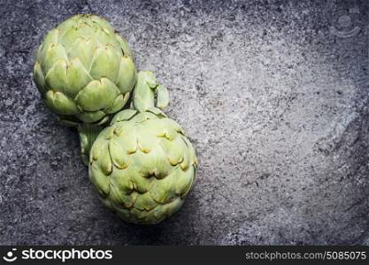 Green Artichokes on gray concrete background, top view. Superfood concept