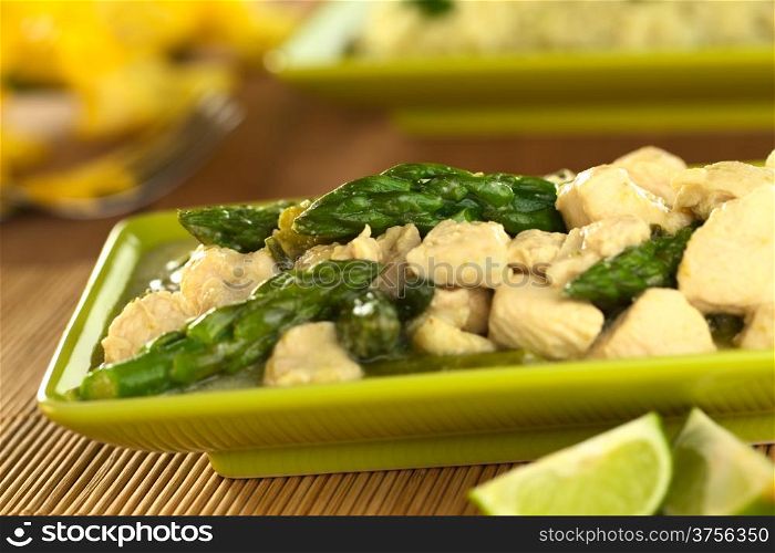 Green asparagus and chicken fricassee with rice in the back (Selective Focus, Focus on the asparagus tip in the middle of the image). Asparagus Chicken Fricassee
