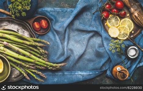 Green asparagus and vegetables cooking ingredients on dark blue rustic background, top view, place for text, banner