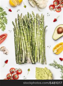 Green asparagus bunch with vegetables ingredients on white background, top view, flat lay. Healthy vegetarian food concept