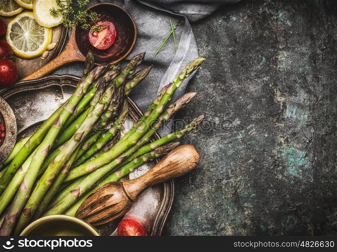 Green asparagus cooking preparation with cooking spoon and ingredients on rustic background, top view, place for text