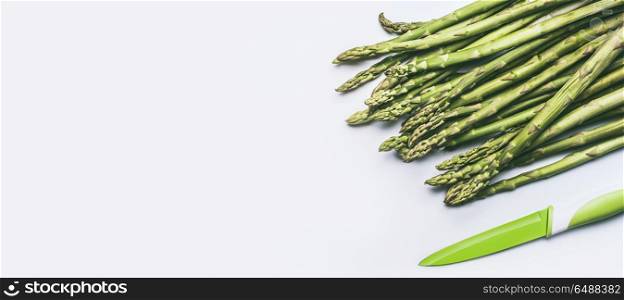 Green asparagus with kitchen knife on white background, top view, flat lay. Healthy seasonal food