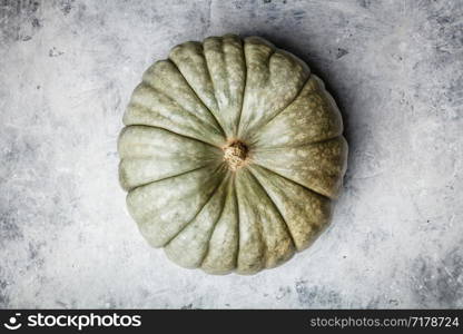 Green autumn pumpkin on grey concrete background, flat lay. Green autumn pumpkin on grey concrete background