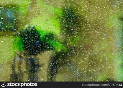 green background from raindrops on window glass during night rain