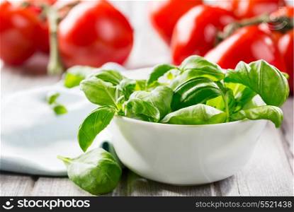 green basil leaves on a bowl and tomatoes