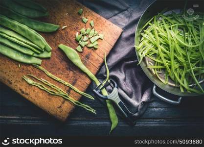 Green beans cooking preparation on dark rustic kitchen table background, top view