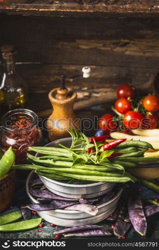 Green beans pods cooking ingredients in bows on rustic kitchen table, side view