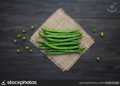 Green beans string on an old wooden black background.Top view.