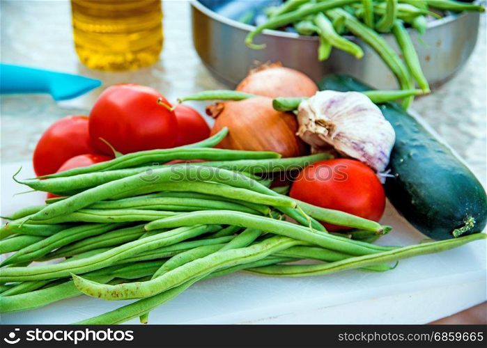 green beans ,tomatoes and garlic, raw on a desk