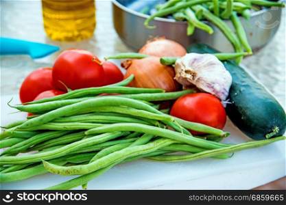 green beans ,tomatoes and garlic, raw on a desk