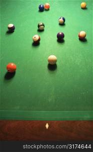 Green billiards table with pool balls spread out.