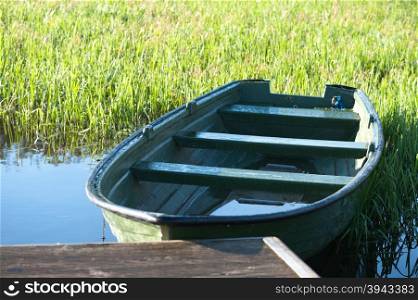 Green boat on the lake near jetty