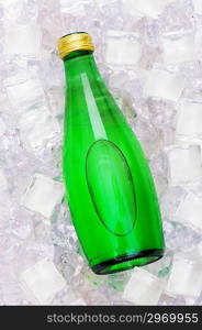 Green bottle of water on ice cubes