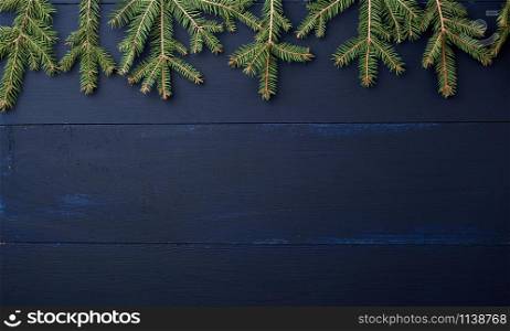 green branches of needles on a dark blue background from wooden boards, festive Christmas background, copy space