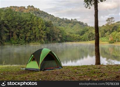 Green camping tent with fog over lake with beautiful view of pine tree forest at Pang Oung national park in Mae Hong Son, Thailand