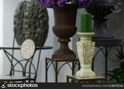 green candle on a candlestick on the marble background of flowers and vases. green candle on a candlestick