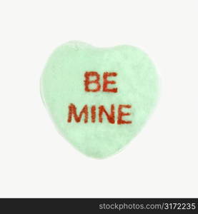 Green candy heart that reads be mine against white background.