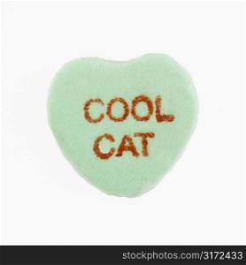 Green candy heart that reads cool cat against white background.