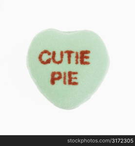 Green candy heart that reads cutie pie against white background.