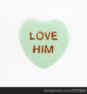 Green candy heart that reads love him against white background.