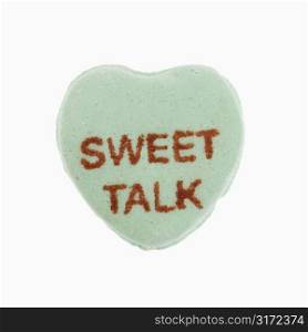 Green candy heart that reads sweet talk against white background.