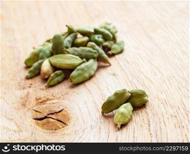 Green cardamom pods heap on wooden board background