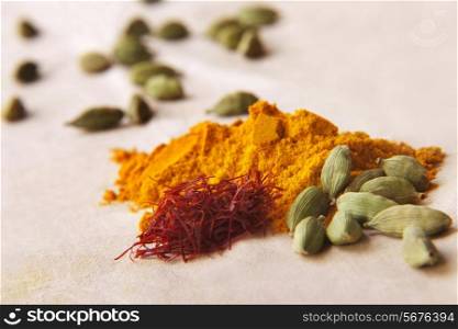 Green cardamom pods, saffron and turmeric powder on cloth
