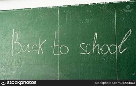 Green chalk blackboard written Back To School with white chalk