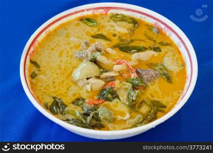 green chicken curry in bowl on blue background