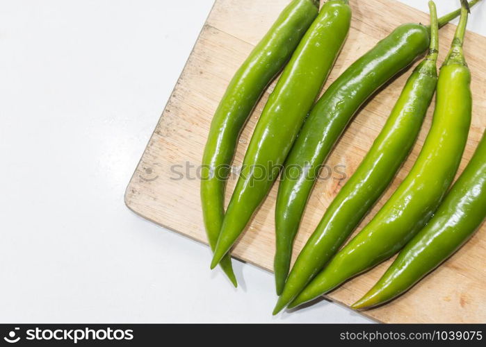 green chilies on a wooden cutting board.