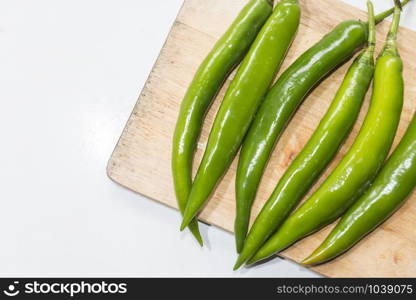 green chilies on a wooden cutting board.