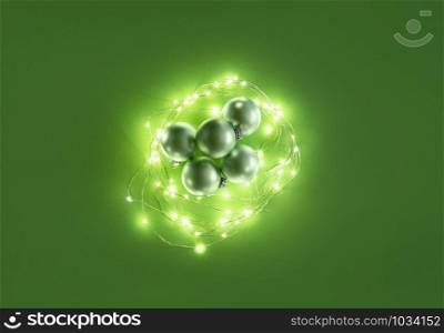 Green Christmas balls and lit Christmas lights on green background. Above view of Xmas ornaments. Flat lay with traditional decorations for Christmas