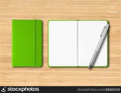 Green closed and open lined notebooks with a pen. Mockup isolated on wooden background. Green closed and open lined notebooks with a pen on wooden background