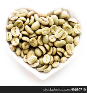 Green coffee beans in the heart shape bowl on a white
