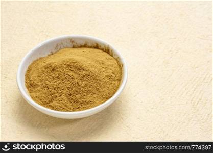 green coffee beans powder - a small bowl against a textured paper background with a copy space