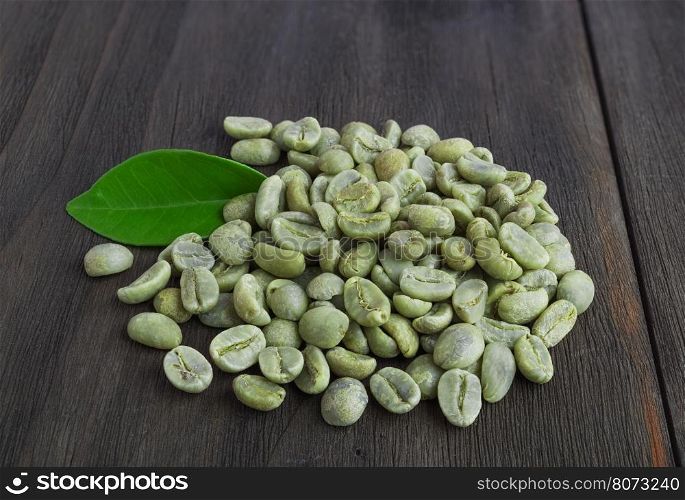 Green coffee beans with leaf on vintage dark wooden surface