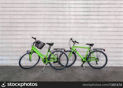 Green colored bicycles against concrete wall with stripes pattern
