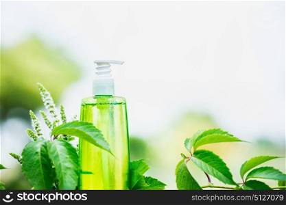 Green cosmetic product bottle with green leaves at nature background, front view. Natural cosmetic product concept, copy space