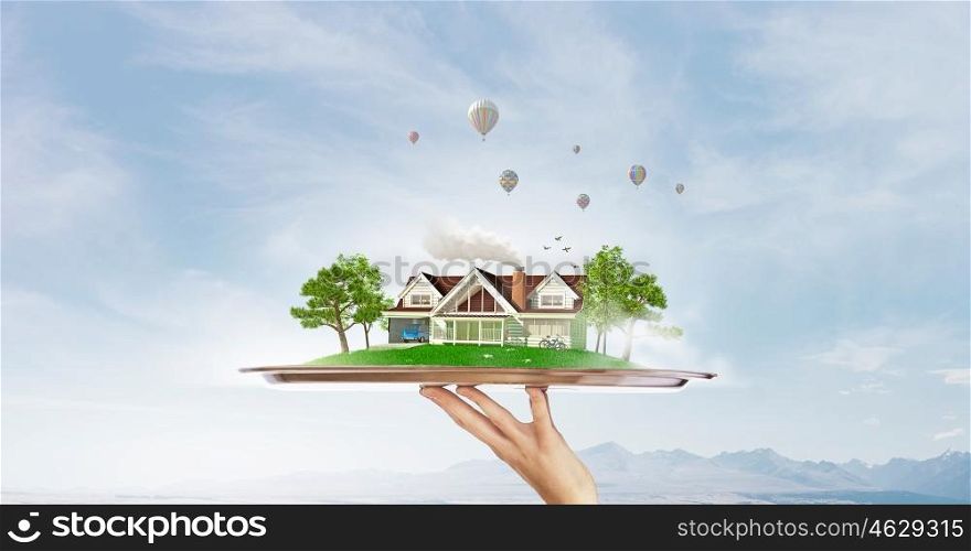 Green countryside life. Hand holding metal tray with model of green construction concept