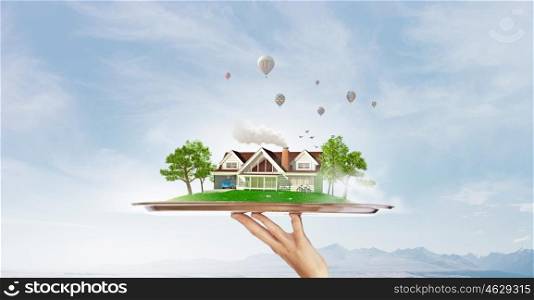 Green countryside life. Hand holding metal tray with model of green construction concept