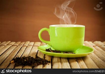 green cup of hot tea on wood background
