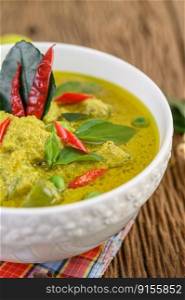 Green curry in a bowl on wooden table.