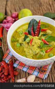 Green curry in a bowl with lime, red onion, lemon grass, garlic and kaffir lime leaves