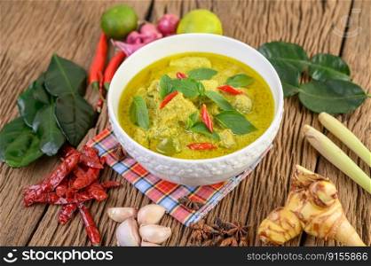 Green curry in a bowl with lime, red onion, lemon grass, garlic and kaffir lime leaves