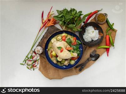Green curry with Chicken and Green-white varieties of Thai eggplants (Kaeng khiao wan) in Ceramic bowl served with Thai rice noodles (Fermented rice flour noodles). Authentic thai food, Top view, Copy space, Selective focus.