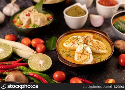 Green curry with eggs in black cups, with lemon, lemongrass, chili, and tomatoes.