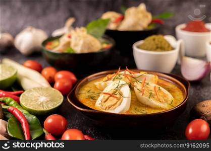 Green curry with eggs in black cups, with lemon, lemongrass, chili, and tomatoes.