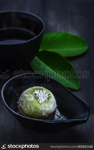 Green Daifuku Mochi Japanese dessert on dish served with hot tea , still life